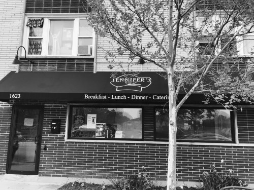 A black and white image of a restaurant facade with a sign reading "Jennifer's" and hours for breakfast, lunch, and dinner.