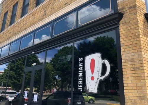 Exterior of a brick building featuring a large window with the sign "Jeremiah's!" and a closed notice.