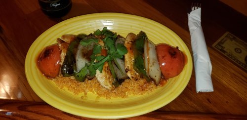 Grilled chicken and vegetables on a yellow plate, served over rice, garnished with cilantro.