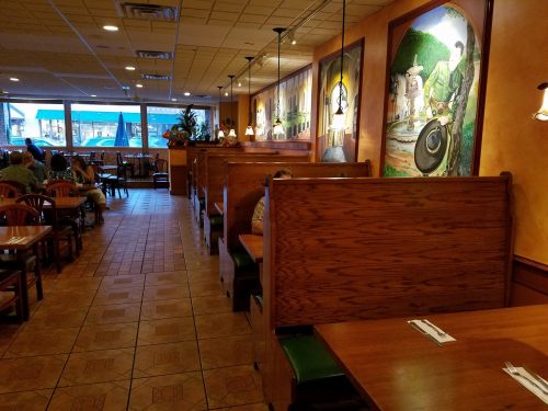Interior of a restaurant featuring wooden booths, murals on the walls, and a cozy dining atmosphere.