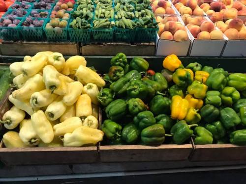 A variety of colorful peppers, including yellow, green, and white, displayed in wooden crates at a market.