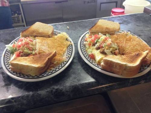 Two plates of food featuring toasted bread, shredded cheese, diced tomatoes, and a side of hash browns.