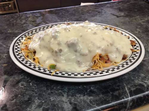 A plate of spaghetti topped with a creamy white sauce and ground meat, served on a checkered platter.