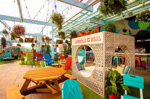 Colorful outdoor seating area with plants, hanging flowers, and a cozy nook that says "Cuddles is Real."