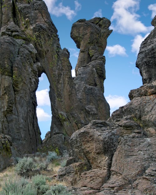 A rocky landscape featuring towering rock formations against a blue sky with scattered clouds.