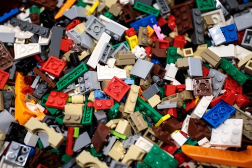A colorful assortment of LEGO bricks in various shapes and sizes, scattered together in a mixed pile.