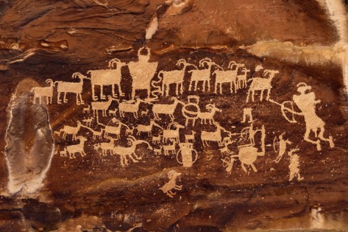 Petroglyphs depicting various animals and human figures carved into a rocky surface, showcasing ancient artistry.