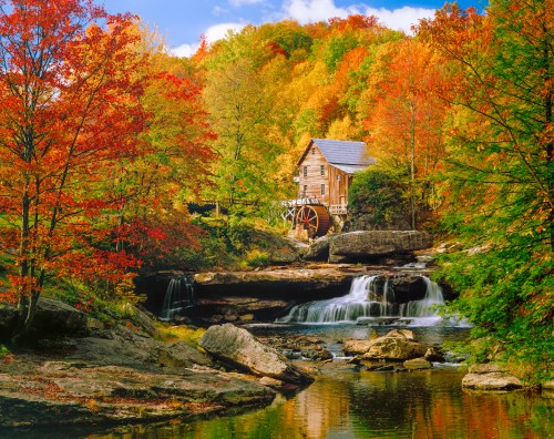A scenic autumn landscape featuring a wooden mill beside a waterfall, surrounded by colorful trees and a calm river.