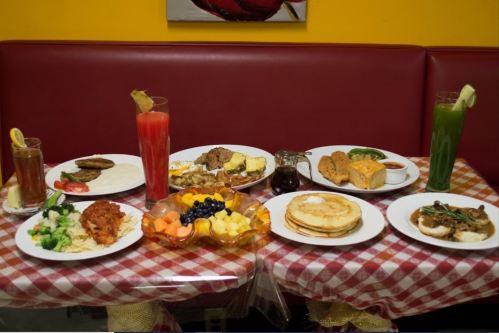 A colorful spread of various dishes, including fruits, pancakes, and drinks, on a checkered tablecloth.