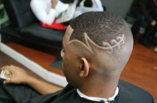 A close-up of a man's stylish haircut featuring intricate designs shaved into the sides.