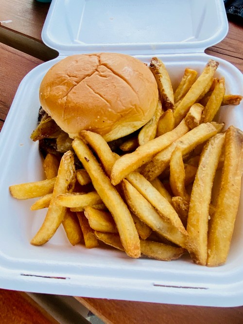 A takeout container with a burger and a generous serving of golden fries.