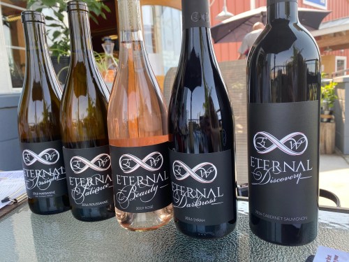Five bottles of wine labeled "Eternal" in various styles, including a rosé and a Cabernet Sauvignon, displayed outdoors.