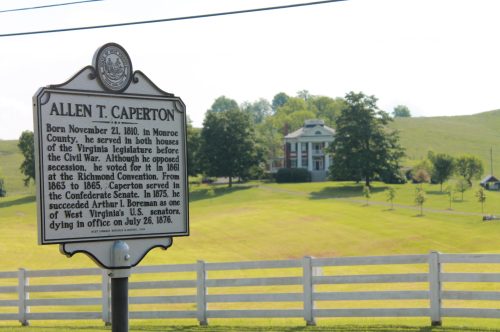 Historical marker for Allen T. Caperton with a scenic view of a house and green hills in the background.