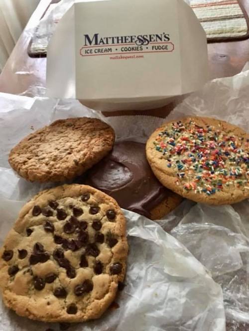 A variety of large cookies, including chocolate chip, fudge, and sprinkle-topped, next to a box from Mattheessen's.