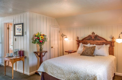 Cozy bedroom with a queen bed, floral arrangement, and warm lighting, featuring wooden accents and a welcoming atmosphere.