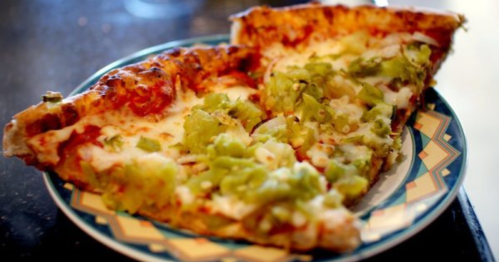 Two slices of pizza topped with melted cheese and green peppers on a decorative plate.