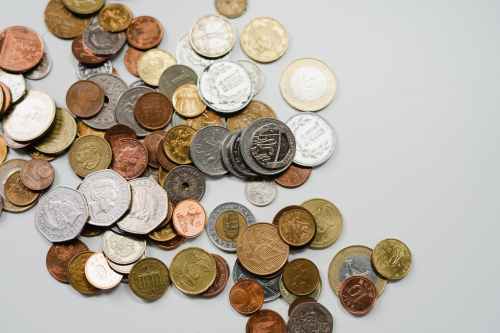 A scattered collection of various coins in different sizes and colors on a light background.
