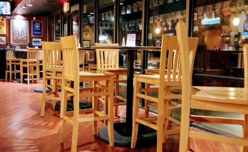 Empty restaurant interior with wooden chairs and tables, featuring a warm ambiance and large windows.