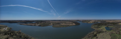 A panoramic view of a serene river landscape with lush greenery and clear blue skies.
