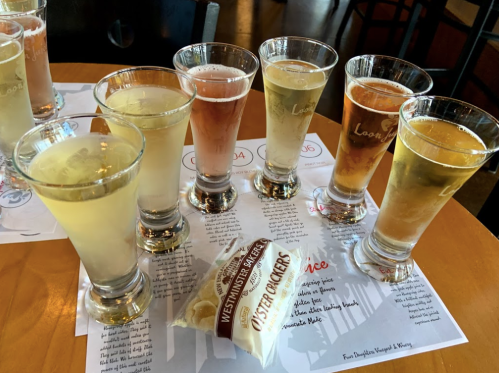 A selection of craft beers in tasting glasses, with a pack of oyster crackers on a wooden table.