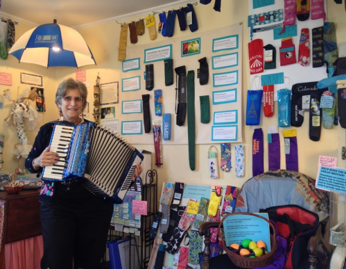 A woman plays an accordion in a colorful room filled with various socks and art displays.