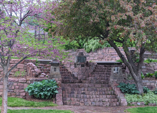 Stone steps surrounded by lush greenery and flowering trees, creating a serene garden landscape.