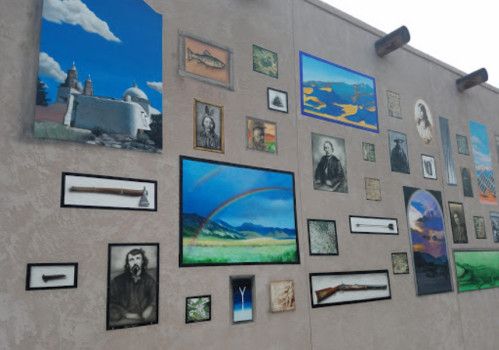 A mural featuring various framed paintings and photographs, including landscapes, historical figures, and artifacts.