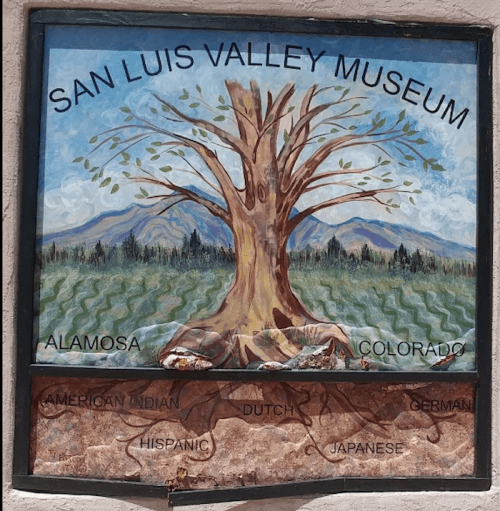 Mural of a tree with roots labeled by cultural groups, titled "San Luis Valley Museum" in Alamosa, Colorado.