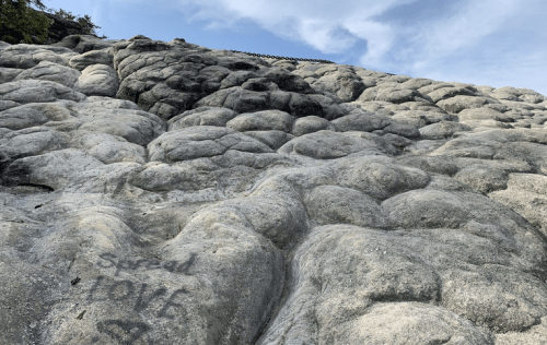 A rocky surface with a chain in the background and the words "Spread Love" etched into the stone.