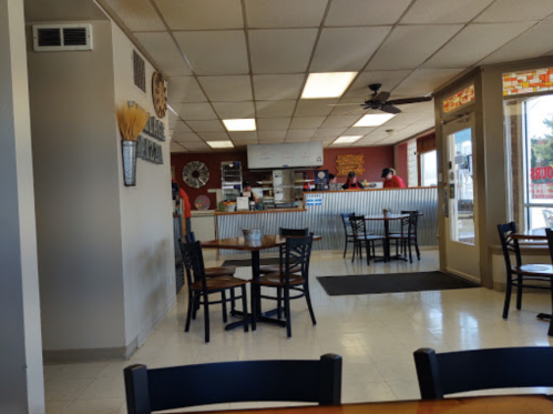 Interior of a casual dining restaurant with tables, a counter, and staff in the background. Bright and welcoming atmosphere.