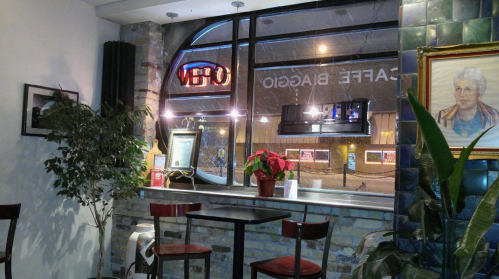 Cozy café interior with a window showing snow outside, plants, and a "OPEN" sign illuminated.