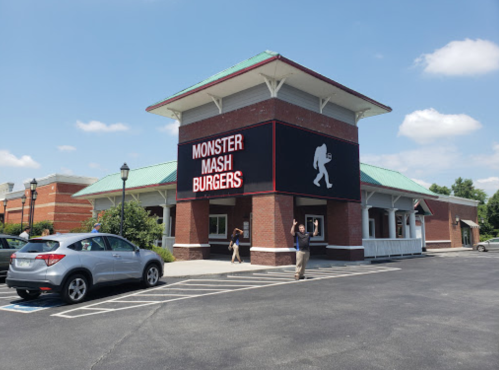 A restaurant building with a sign reading "Monster Mash Burgers" and people outside on a sunny day.
