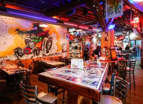 A vibrant restaurant interior with colorful murals, wooden tables, and a lively atmosphere filled with patrons.