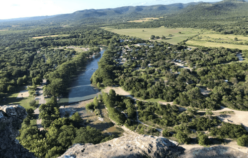 Aerial view of a lush green landscape with a winding river and a small community nestled among trees.