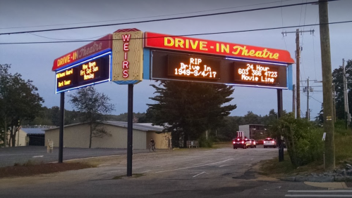 A vintage drive-in theater marquee displaying "RIP Drive-In 1949-94/17" and a movie line phone number.