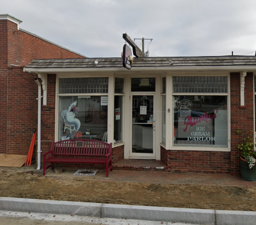 A brick ice cream parlor with a sign reading "Auntie's Ice Cream Parlor" and a bench outside.