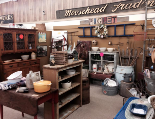 A vintage shop display featuring rustic furniture, kitchenware, and decorative items in a cozy setting.