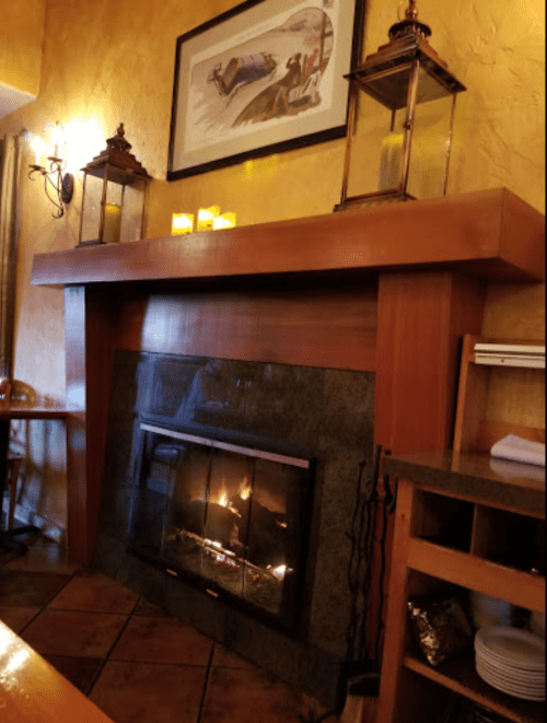 Cozy restaurant interior featuring a stone fireplace, wooden mantel, and decorative lanterns.