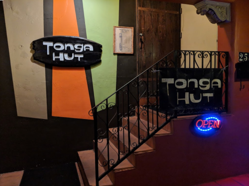 Entrance to Tonga Hut with colorful walls, a staircase, and an illuminated "OPEN" sign.