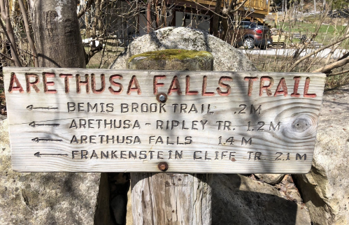 Wooden signpost indicating trails: Arethusa Falls Trail, Bemis Brook Trail, Arethusa-Ripley Trail, and Frankenstein Cliff Trail.
