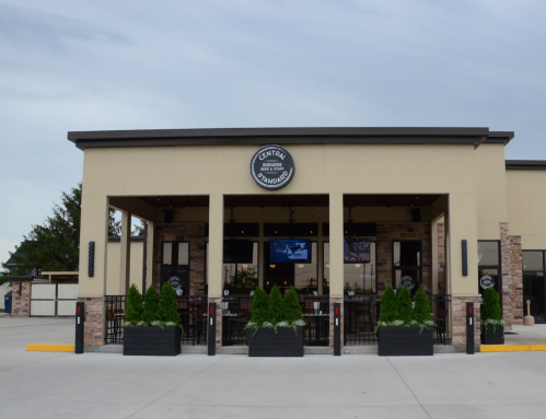 Exterior view of a restaurant with a sign reading "Central" and potted plants at the entrance under a cloudy sky.