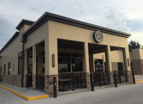 Exterior view of a modern restaurant with a stone facade and outdoor seating area.