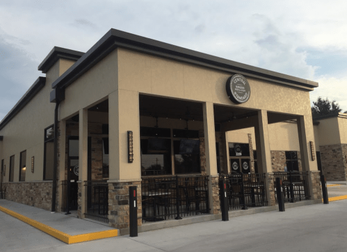 Exterior view of a modern restaurant with a stone facade and outdoor seating area.