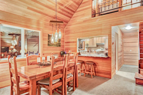 Cozy wooden interior of a cabin with a dining table, kitchen view, and warm lighting.