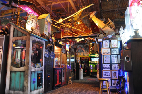A colorful arcade filled with vintage games, memorabilia, and bright neon lights, creating a nostalgic atmosphere.