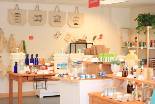 A bright store interior featuring wooden tables with various eco-friendly products and bags displayed on the walls.