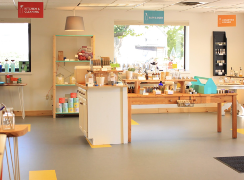 A bright store interior featuring shelves of natural products for kitchen, cleaning, bath, body, and cosmetics.