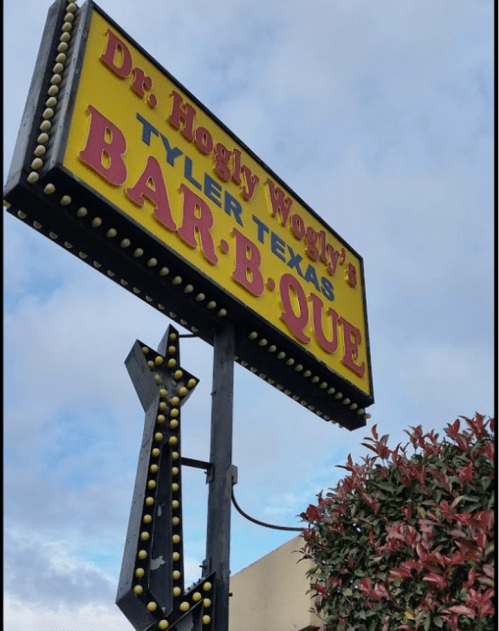 Sign for Dr. Hogly Wogly's Bar-B-Que in Tyler, Texas, featuring bright colors and a decorative arrow.