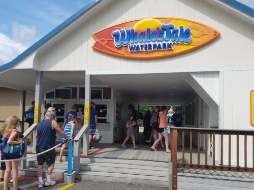 Entrance to Whales Tale Waterpark, with visitors entering and exiting on a sunny day.