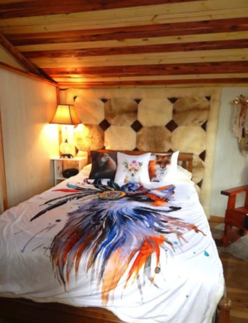 Cozy bedroom featuring a wooden bed with a colorful, artistic blanket and decorative pillows against a rustic backdrop.